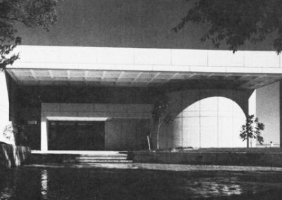 Black and white image of the exterior of the 70's building with trees in front.