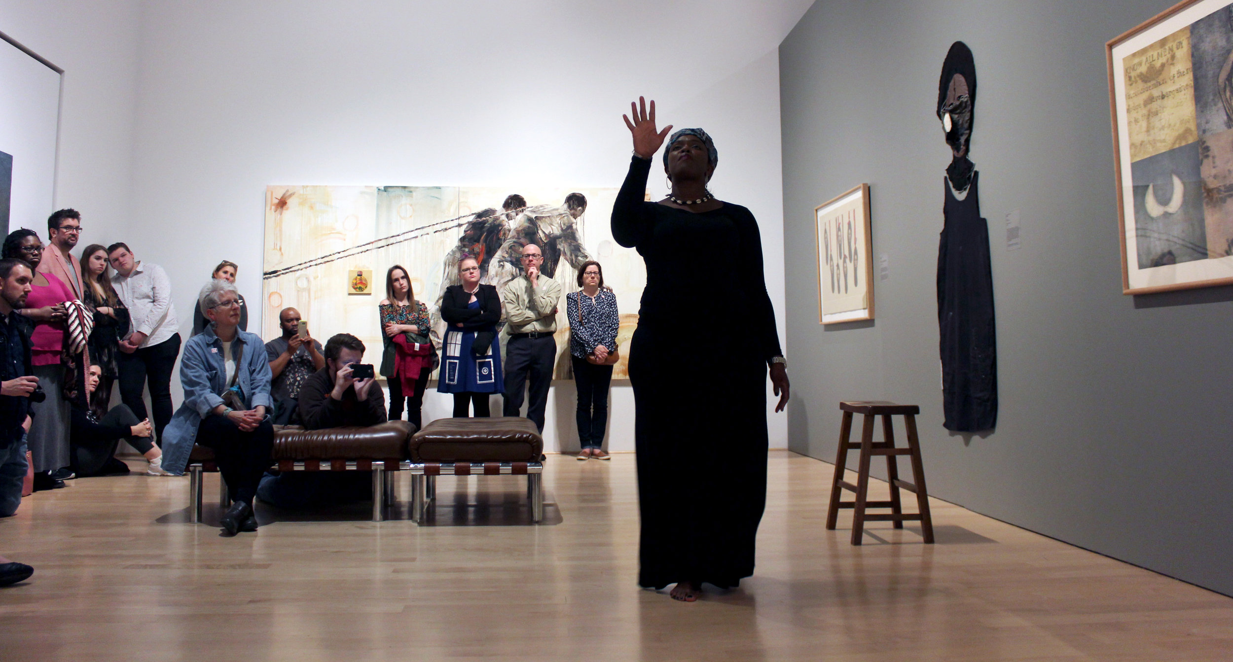 Woman performing in a gallery room full of people.