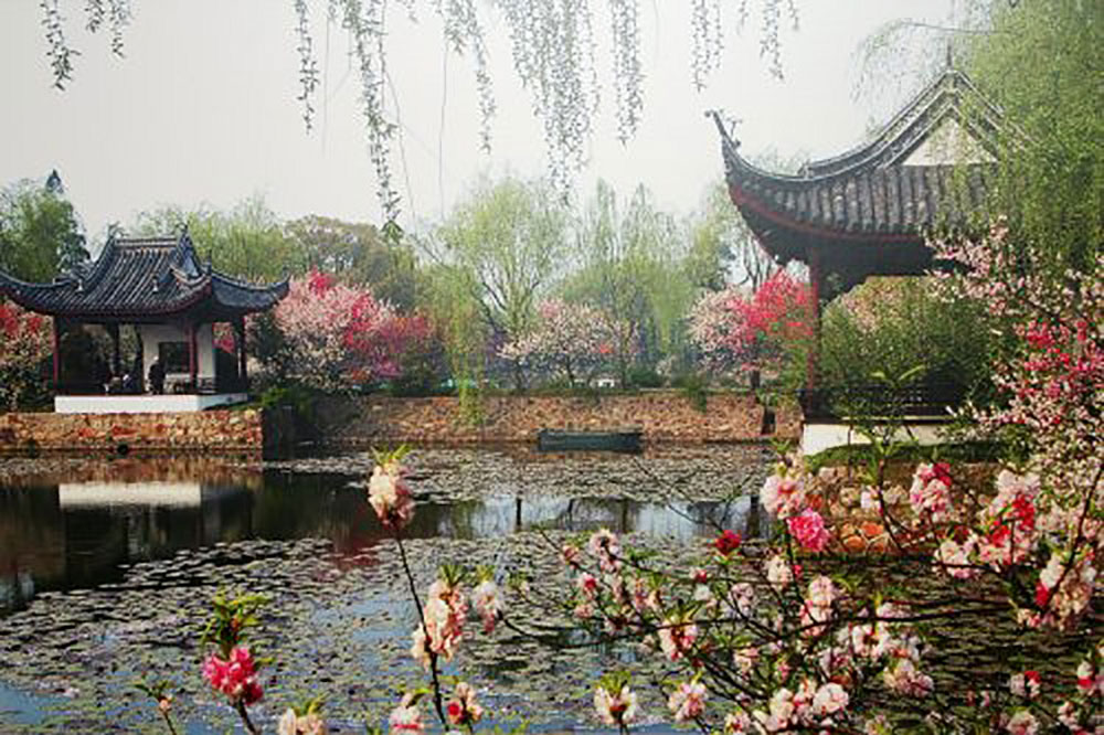 A Chinese garden with buildings and a lake at spring.