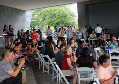 A crowd of people sit in white chairs on the Hunter Museum balcony.