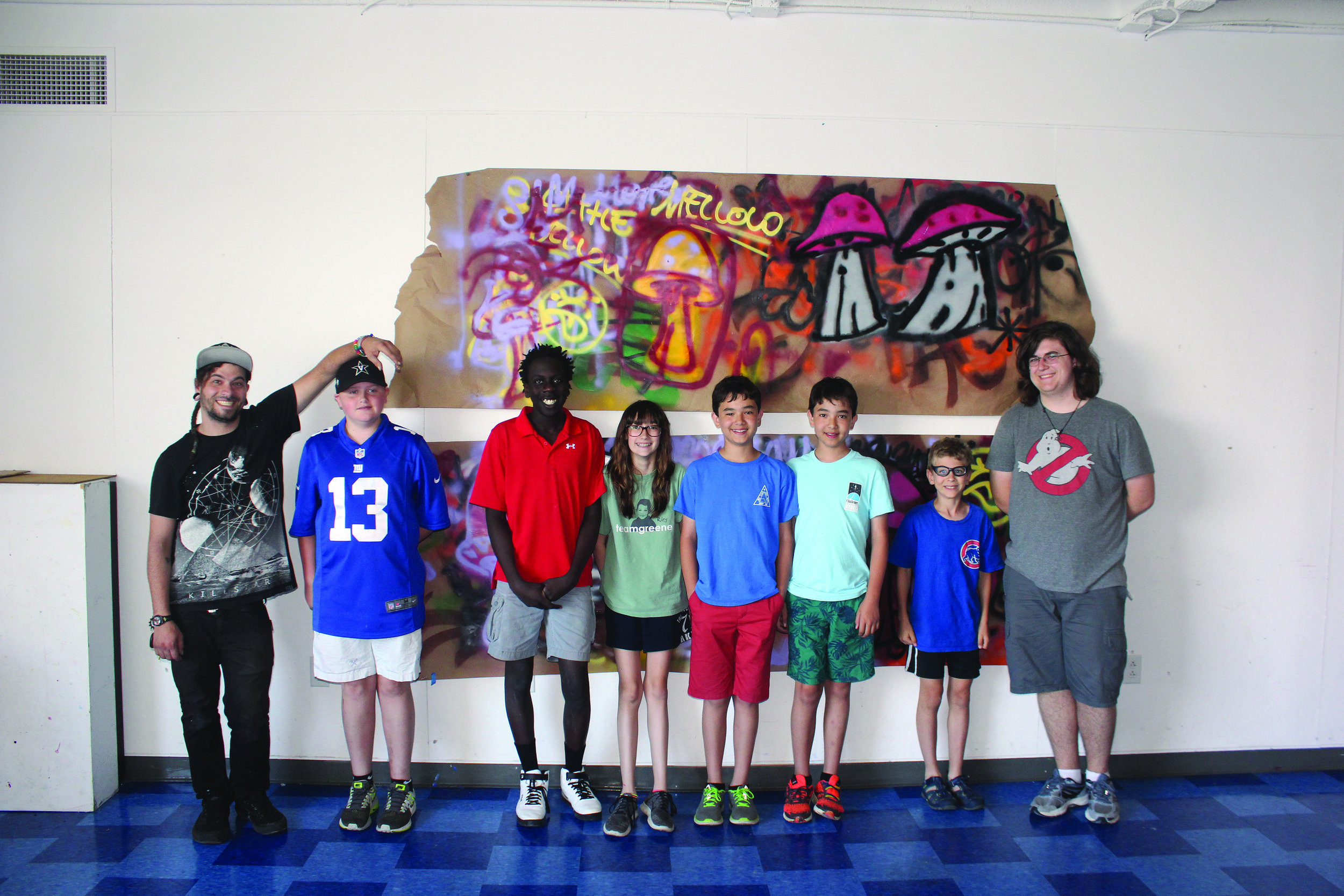 A group of teenagers stand in line for a picture in front of graffiti art.