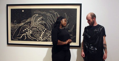 Two people looking at each other standing in front of a piece of art.