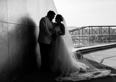 Black and white photo of a bride and groom looking at each other with the pedestrian bridge in the background.