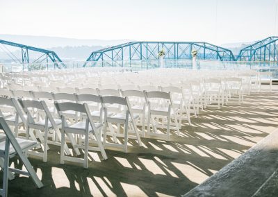 White chairs in rows on the balcony of the Hunter Museum with the pedestrian walking bridge in the background.