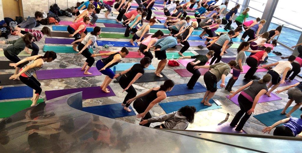 Large crowd of people doing the yoga pose "skier" in the lobby of the Hunter Museum.