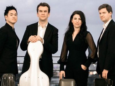 Performers of String Theory wearing black posed with their instruments in cases.