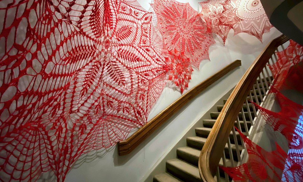 Large red crocheted doilies hung on a wall.